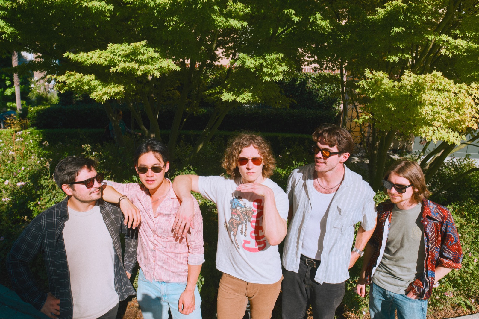 Band posing together outdoors in the sun