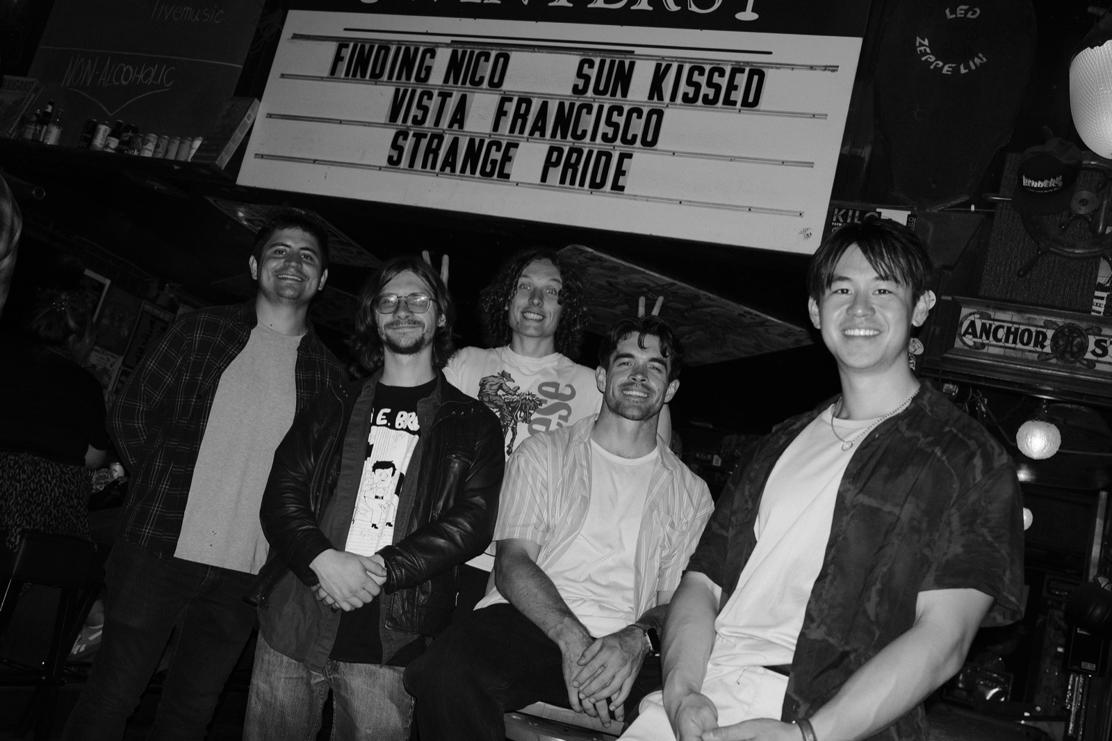 Band posing under marquee sign at venue