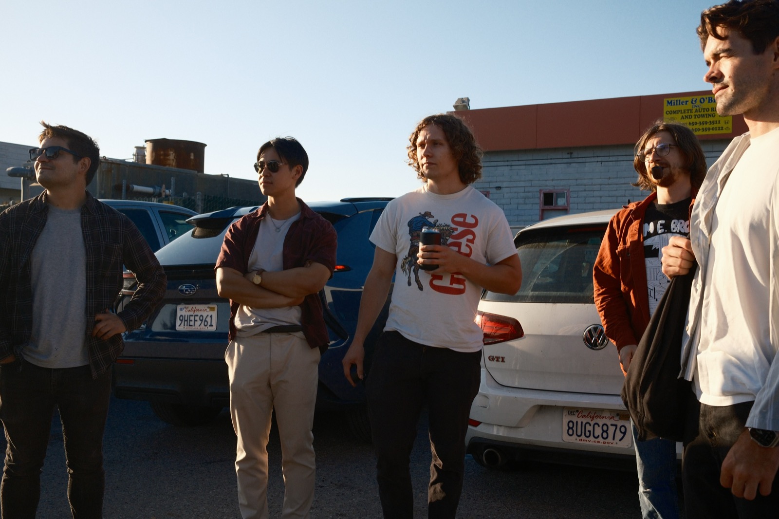 Band members hanging out in a parking lot at sunset