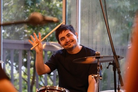 Drummer raising his sticks with a grin at a daytime show