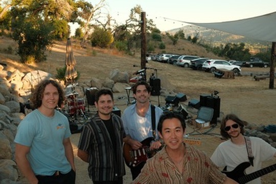 Band posing together at an outdoor show at golden hour