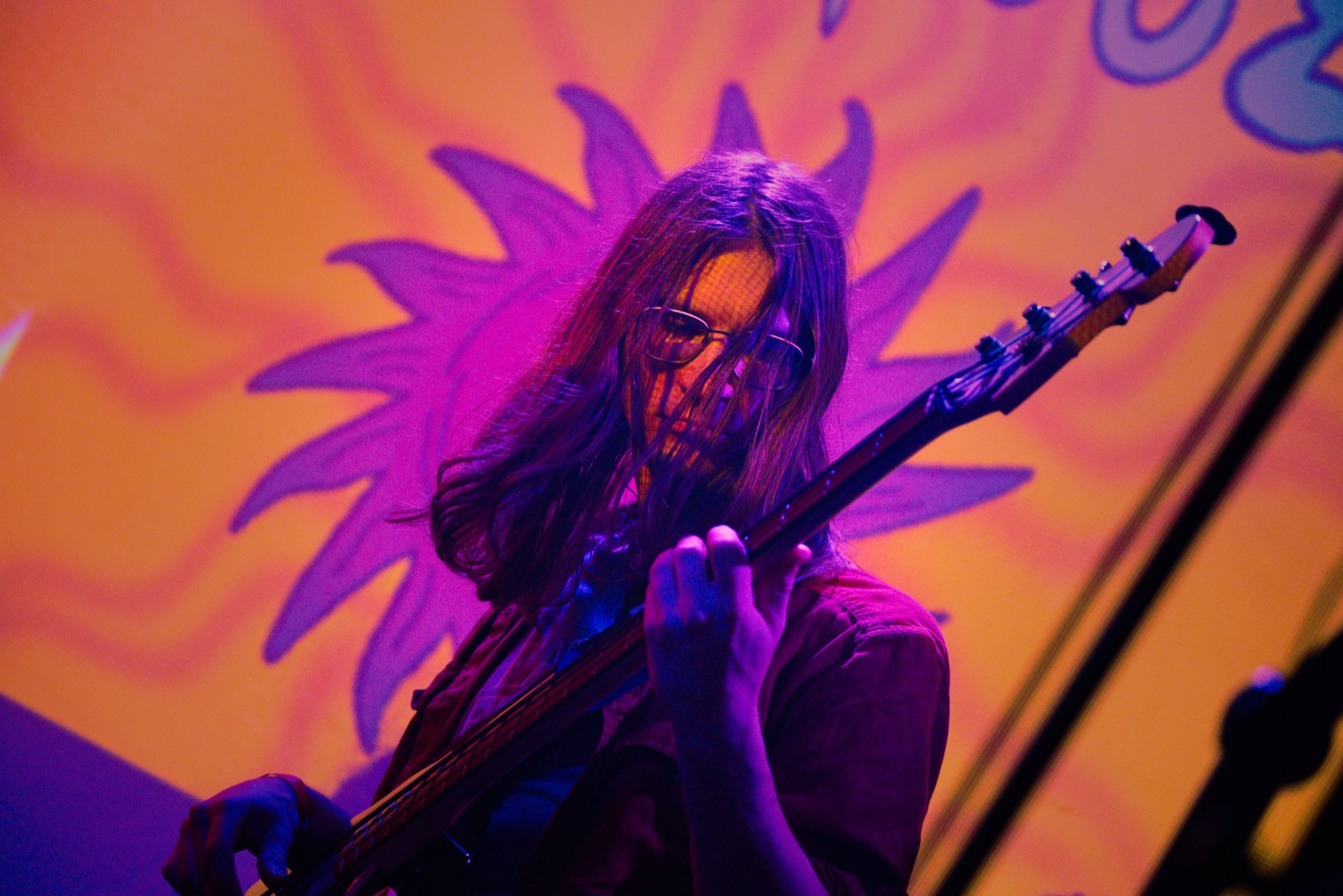 Bassist playing in front of psychedelic sun backdrop